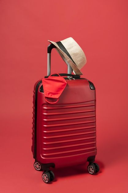 a red piece of luggage with a hat on top