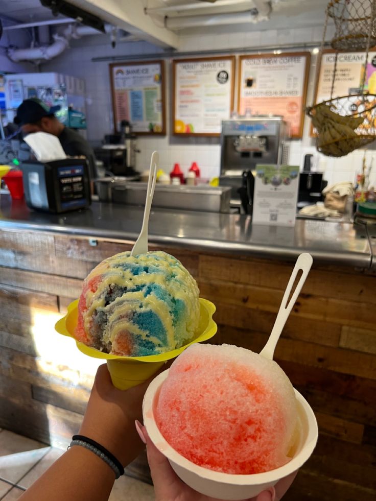 two scoops of ice cream are being held up in front of a counter top