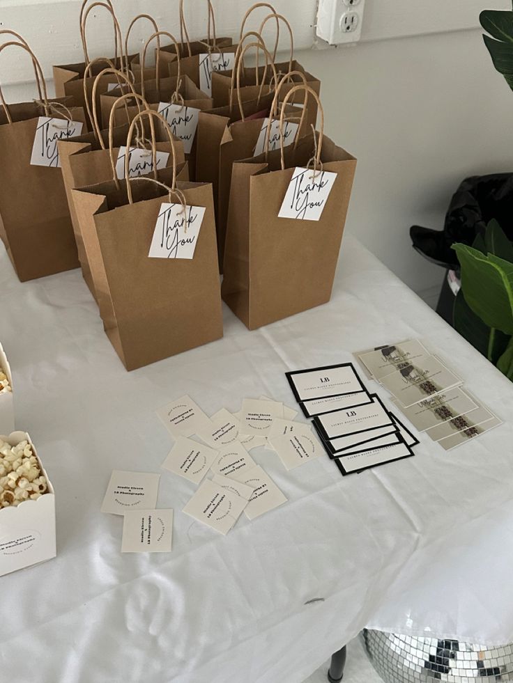 small brown paper bags sitting on top of a white table covered in cards and tags