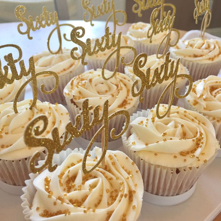 cupcakes with white frosting and gold decorations on a tray that says happy 50th