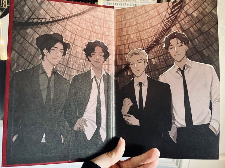 a hand holding an open book with pictures of men in suits and ties on it