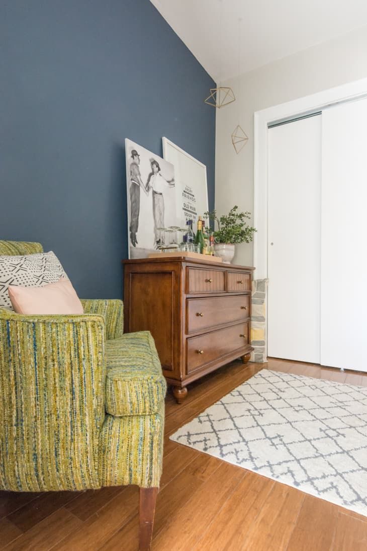 a living room with blue walls and wooden furniture in the corner, including a green chair