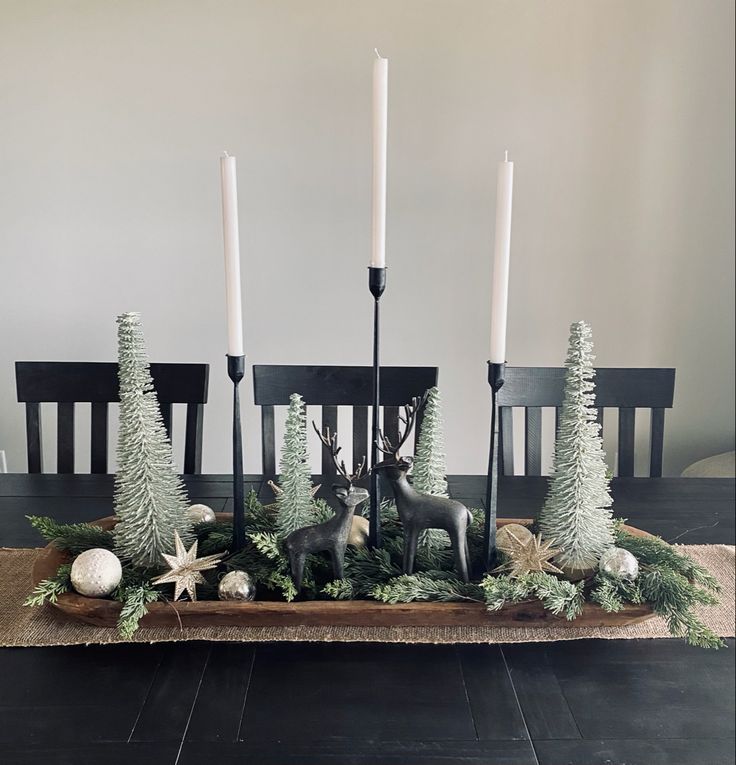 a dining room table with candles and christmas decorations on the centerpiece, along with deer figurines