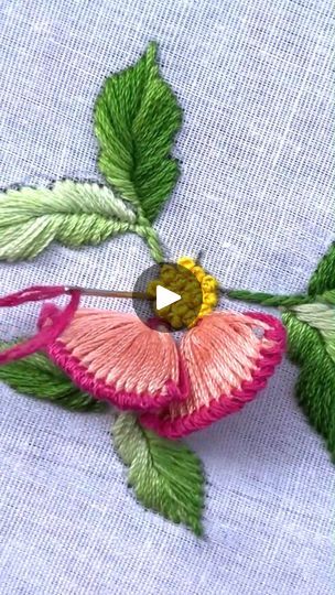 a pink flower with green leaves is on a piece of blue fabric that has been stitched together