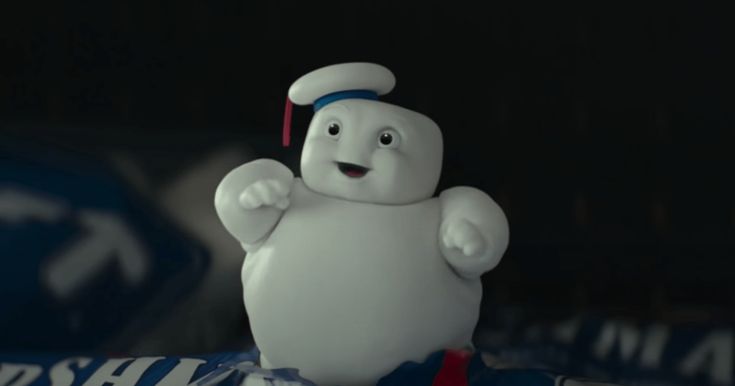 a small white character standing on top of a blue and white sign in the dark