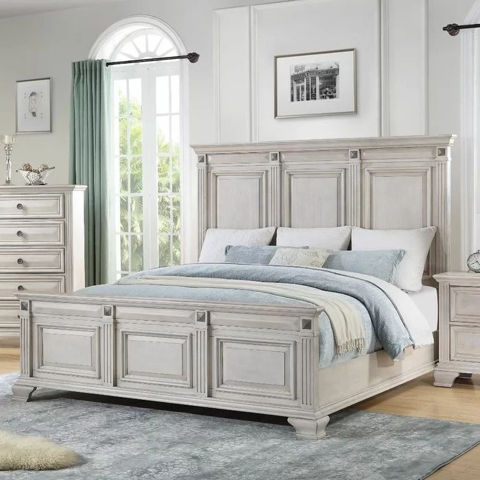 a white bed sitting in a bedroom next to a dresser and mirror on top of a wooden floor