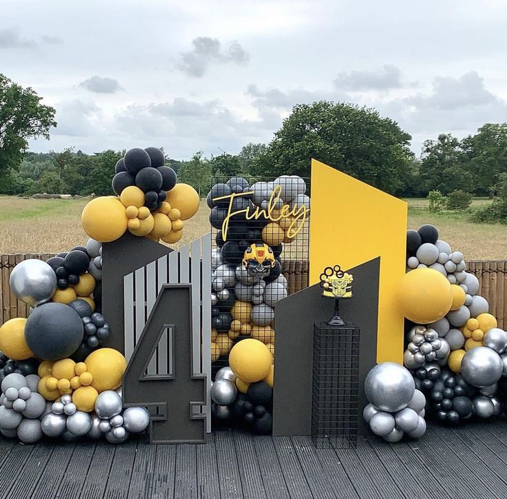 a large number four balloon arrangement on a wooden deck in front of a fence and trees