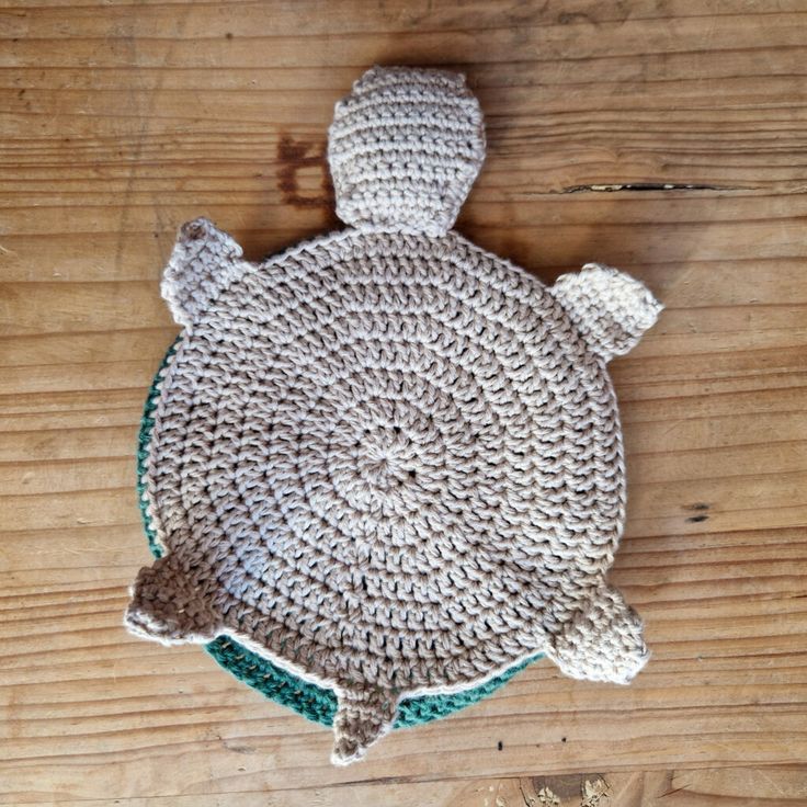 a crocheted turtle hat sitting on top of a wooden table next to a pair of scissors