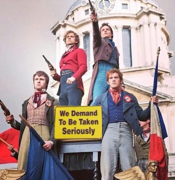 people standing on top of a truck holding flags and pointing to something in the air