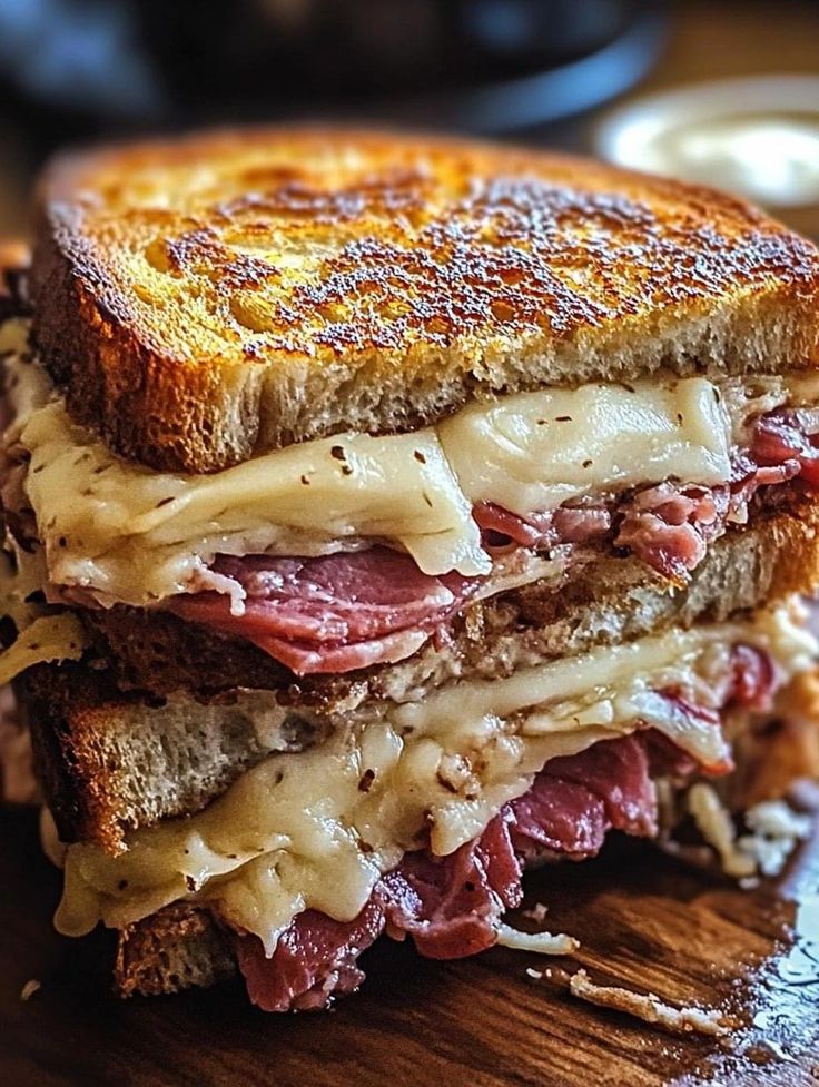 a grilled cheese and meat sandwich on a cutting board