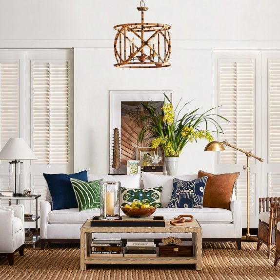 a living room filled with white furniture and lots of green plants on top of it