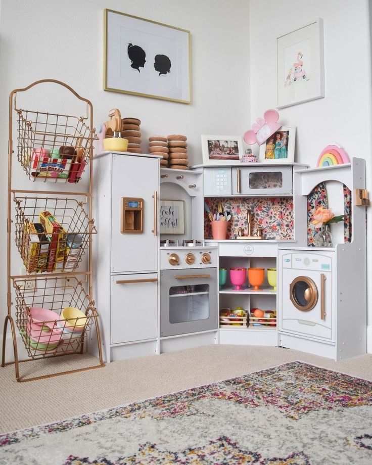 a white play kitchen with lots of toys and accessories on the shelves in front of it