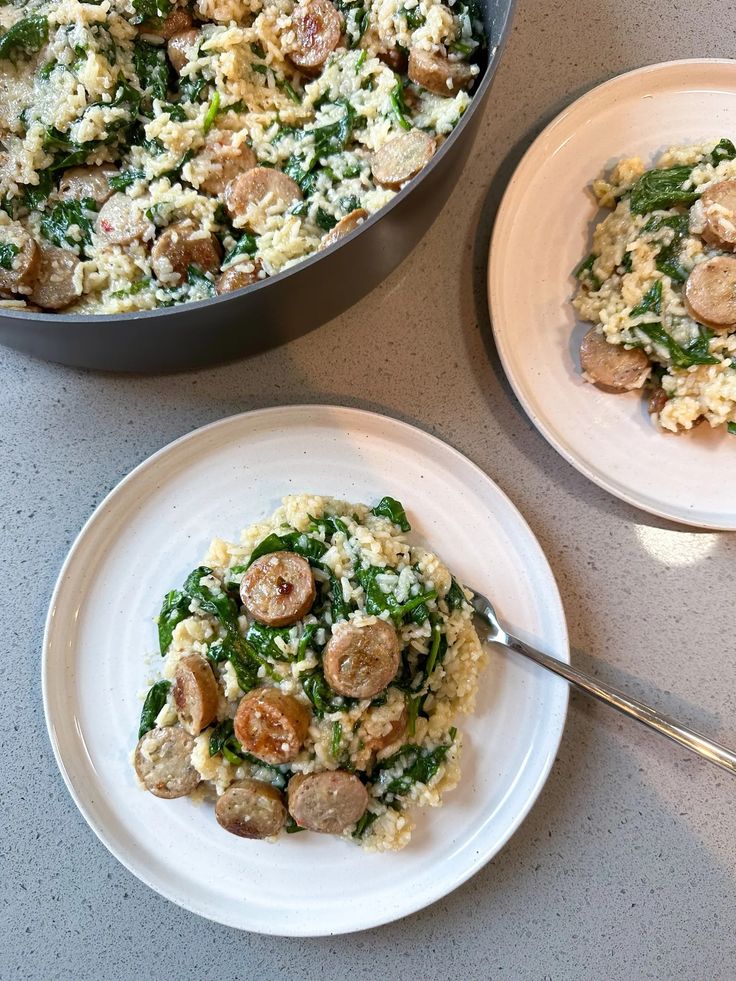 two white plates with food on them next to a pan filled with mushrooms and spinach