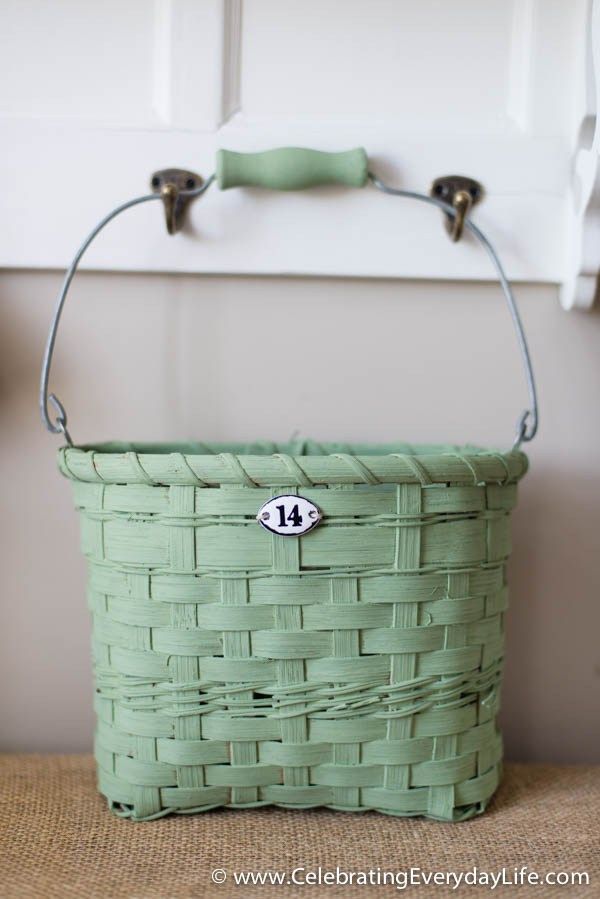 a green basket sitting on top of a table next to a teapot and cup