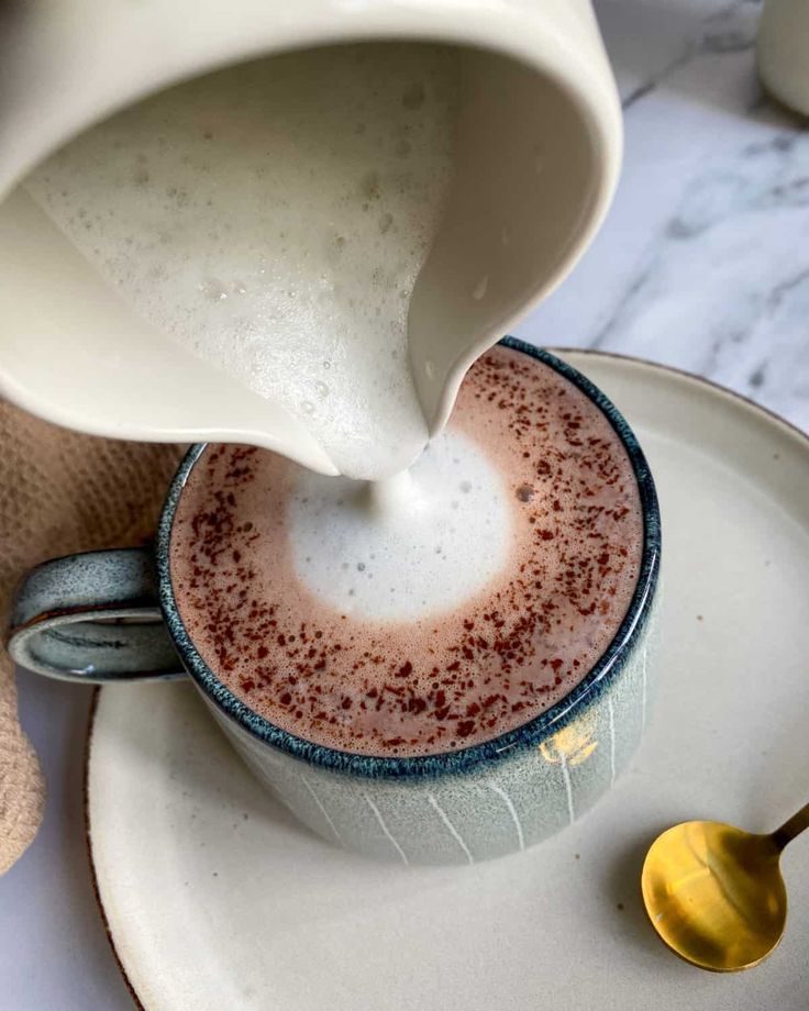 a person pouring milk into a cup on top of a plate