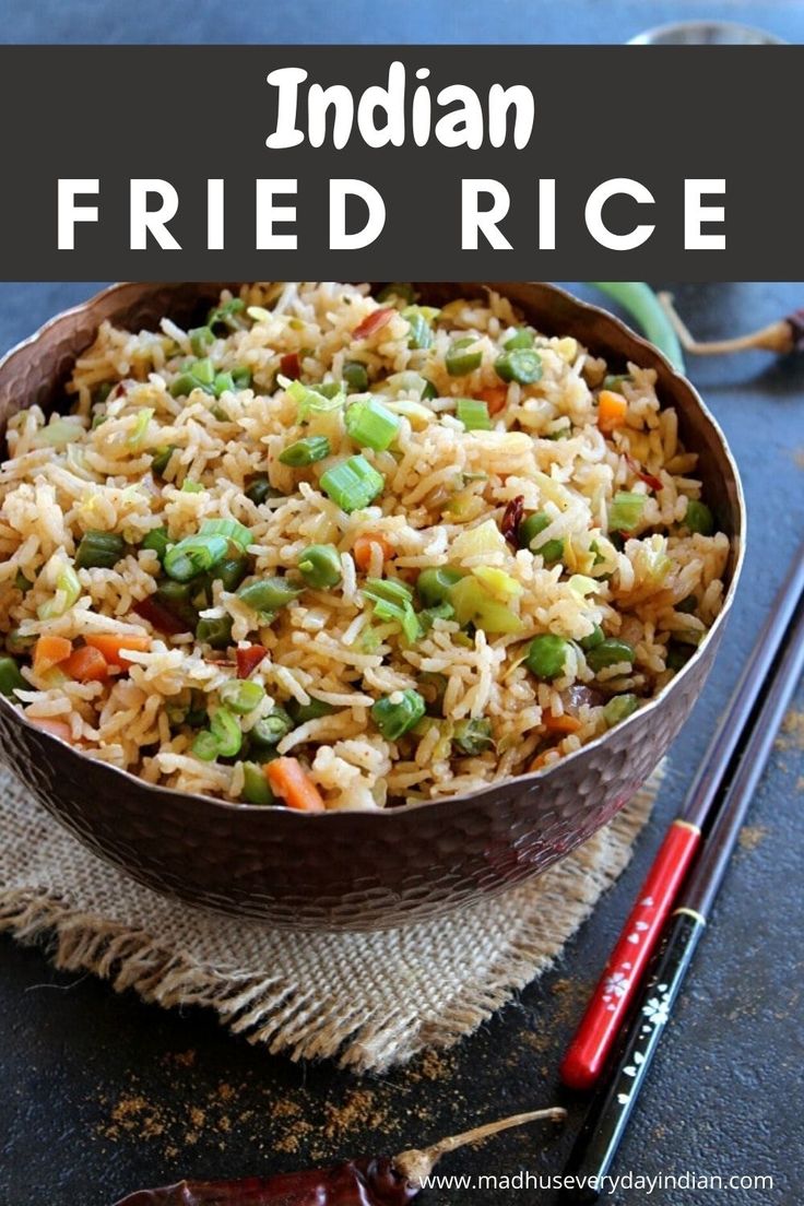 a brown bowl filled with rice and vegetables next to chopsticks on a table