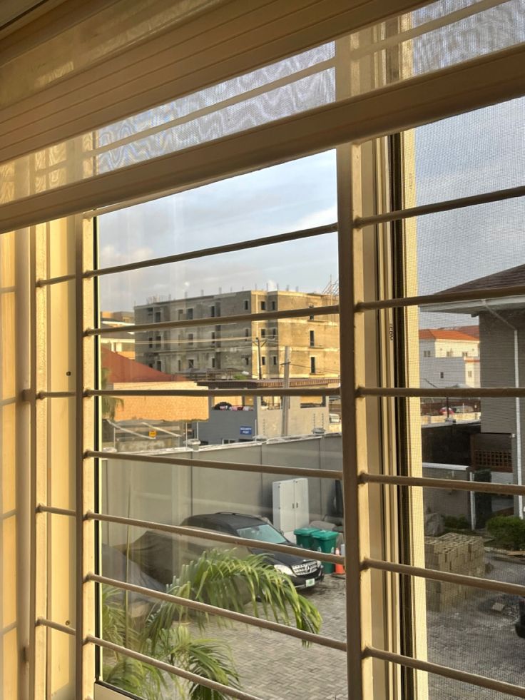 an open window looking out onto a parking lot with cars parked in the street behind it