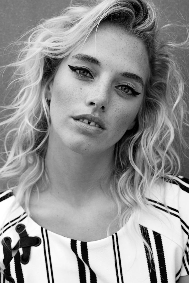 a black and white photo of a woman with wavy hair, wearing a striped shirt