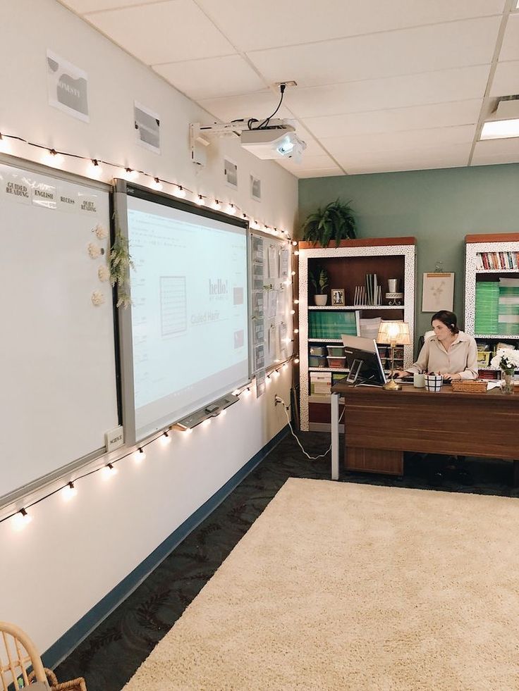 a woman sitting at a desk in front of a projector screen with lights on it