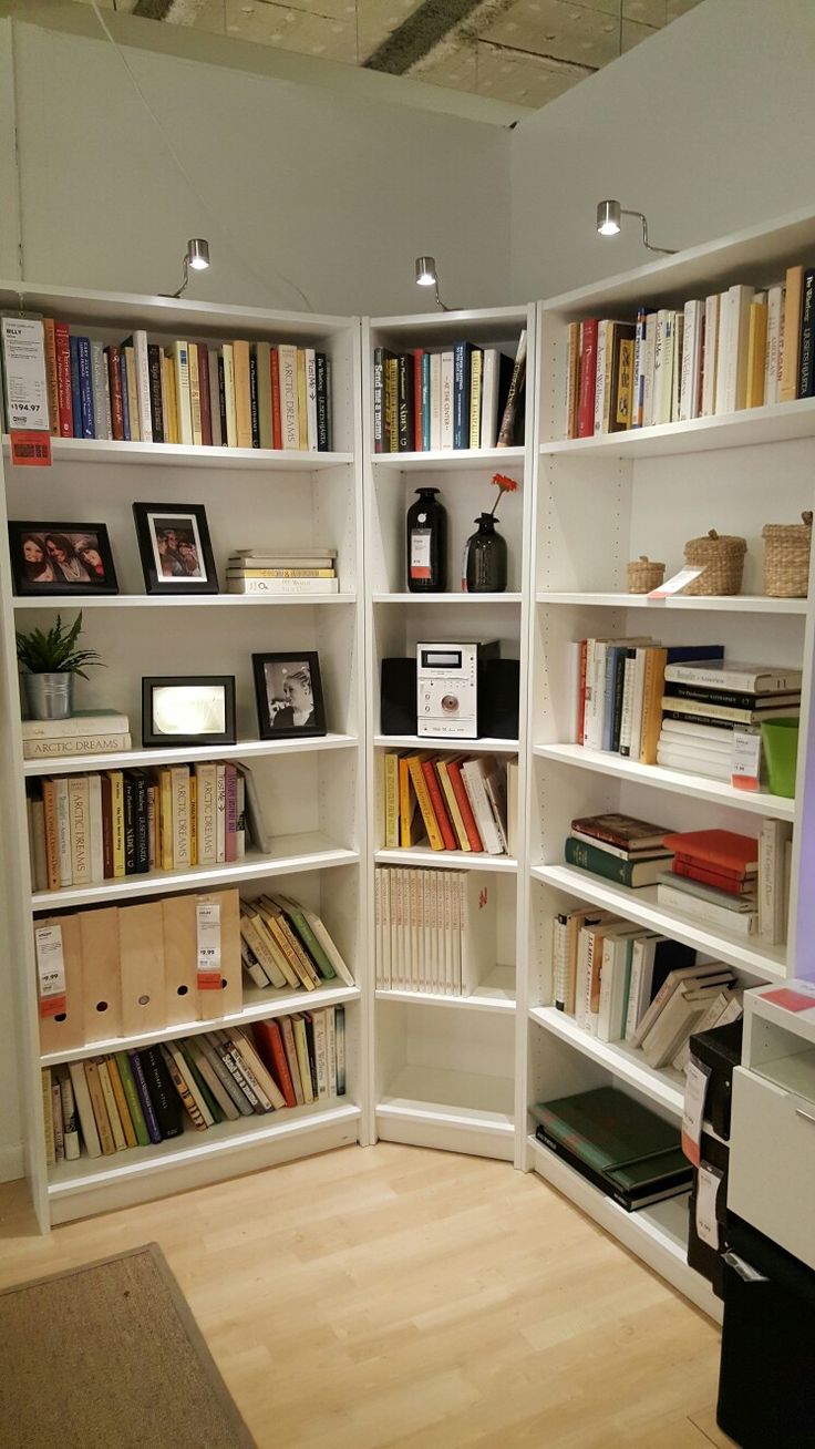 a room filled with lots of white bookshelves next to a desk and chair