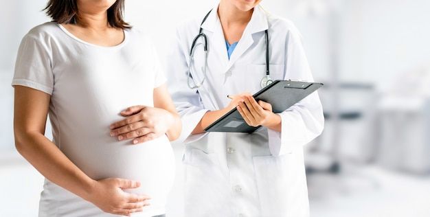 two pregnant women standing next to each other in front of a doctor's stethoscope