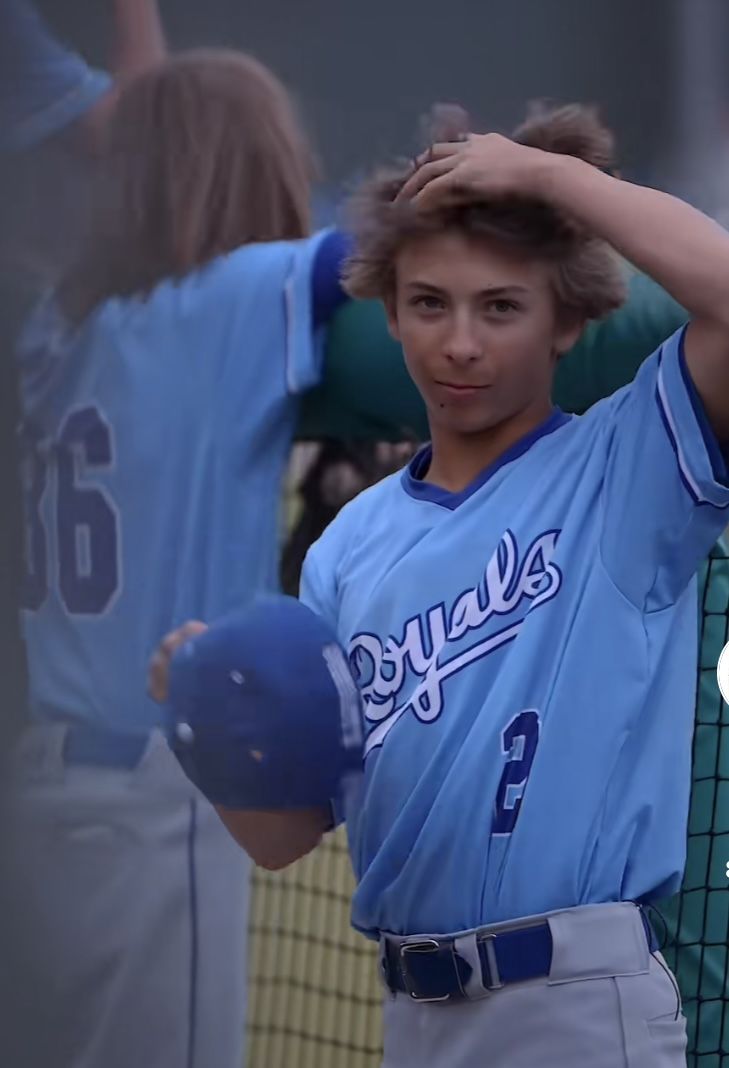 a young baseball player holding his head in the air