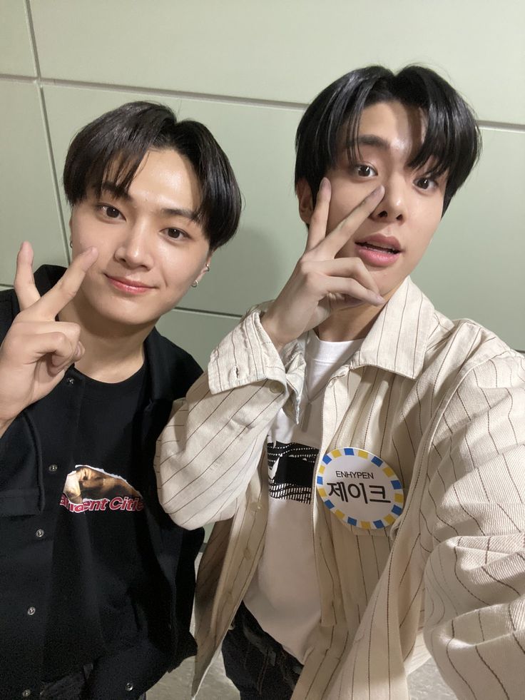 two young men posing for a photo in front of a mirror with their fingers up