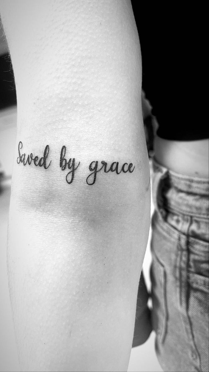 a woman's arm with the words saved by grace tattooed on her left leg