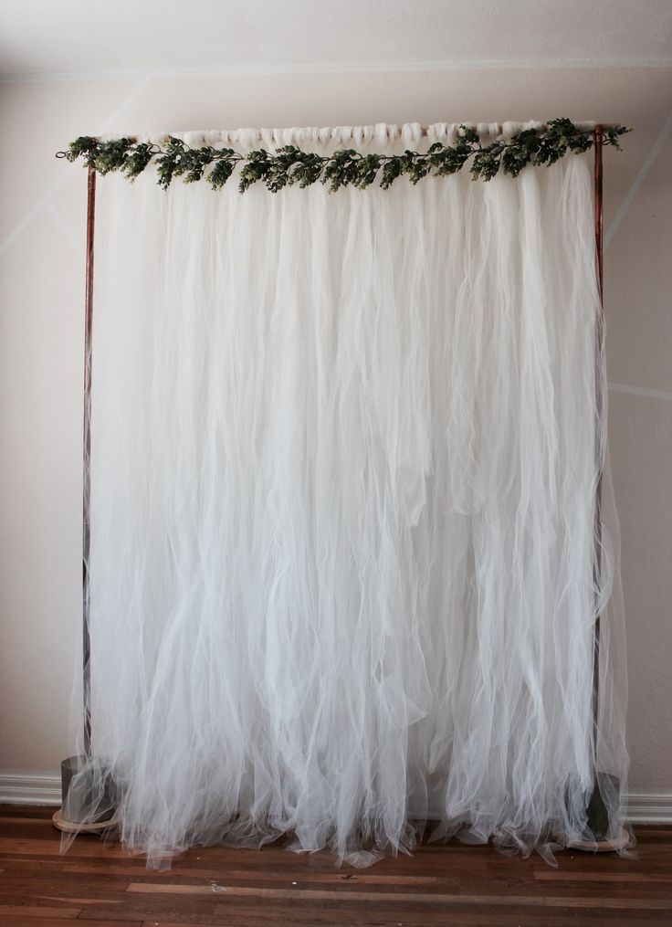 a white curtain with green leaves hanging from it's side in front of a wall