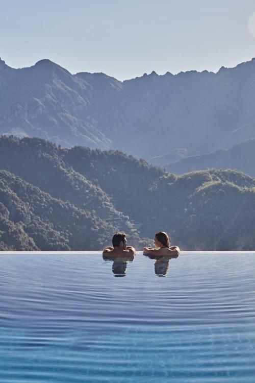 two people in the water with mountains in the background