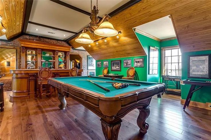 a pool table in the middle of a living room with green walls and wood flooring