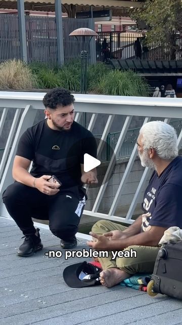 two men sitting on the ground talking to each other