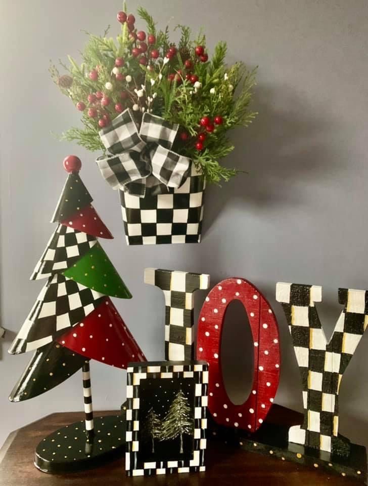 christmas decorations made out of wooden letters on a table with flowers and potted plants