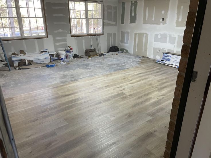 an unfinished room with hard wood floors and windows