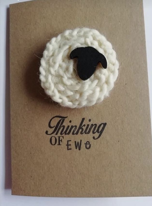 a white and black brooch sitting on top of a brown card that says thinking of ew6