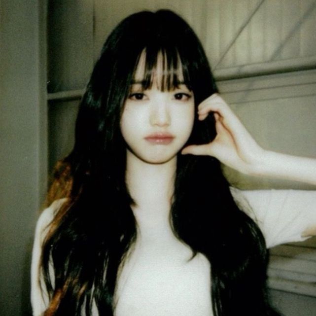 a woman with long black hair and bangs posing for a photo in front of a mirror