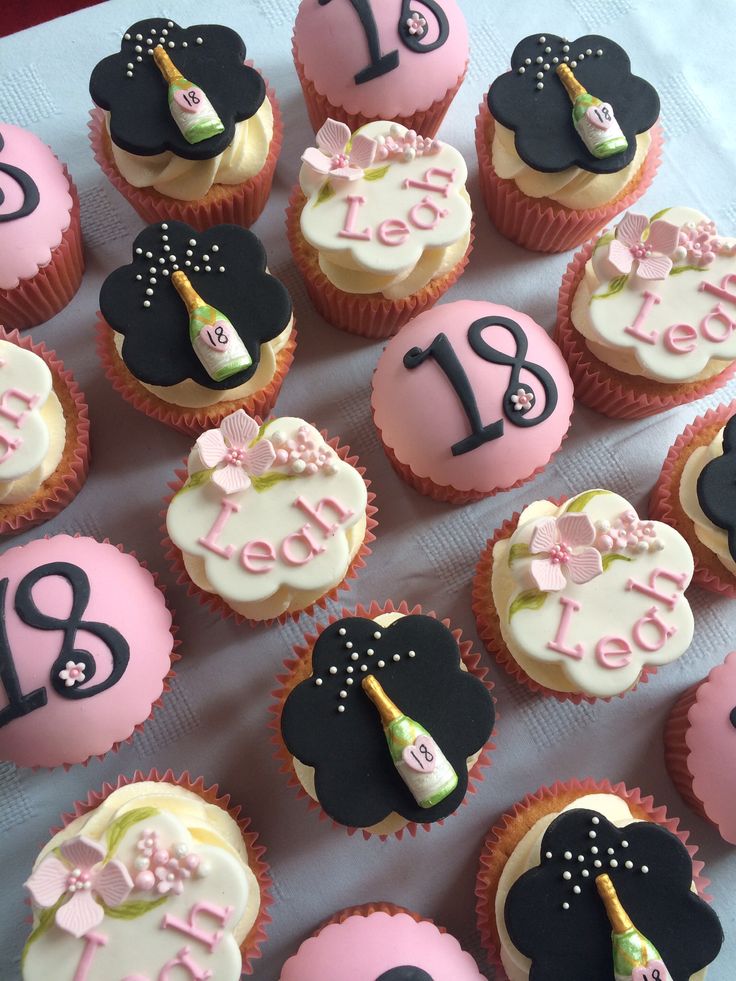 cupcakes decorated with pink and black frosting are arranged on a table top