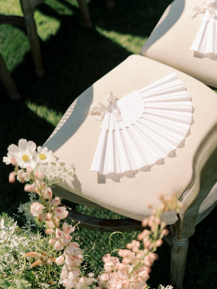 two white chairs sitting on top of a lush green field