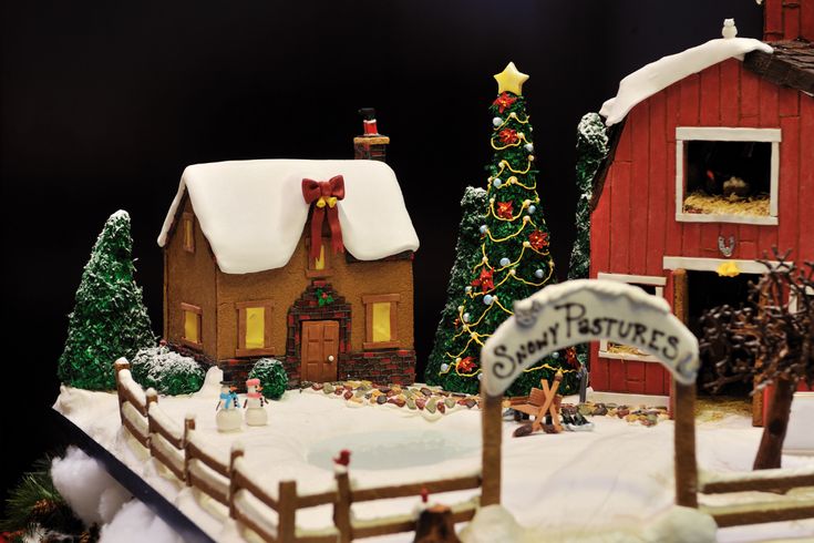 a christmas village with a red barn and snow covered trees