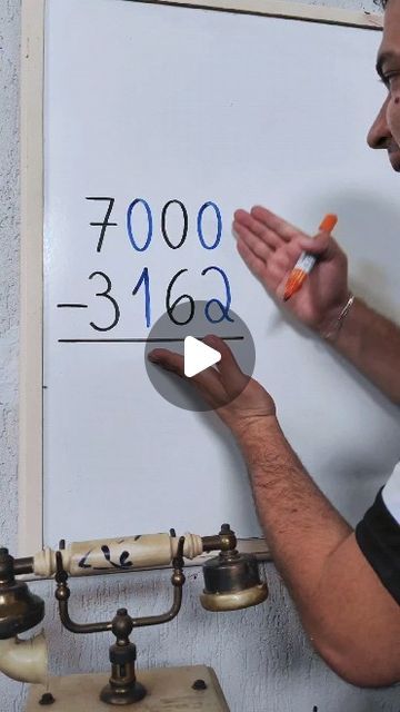 a man writing on a white board with an orange marker in front of him and the numbers below it