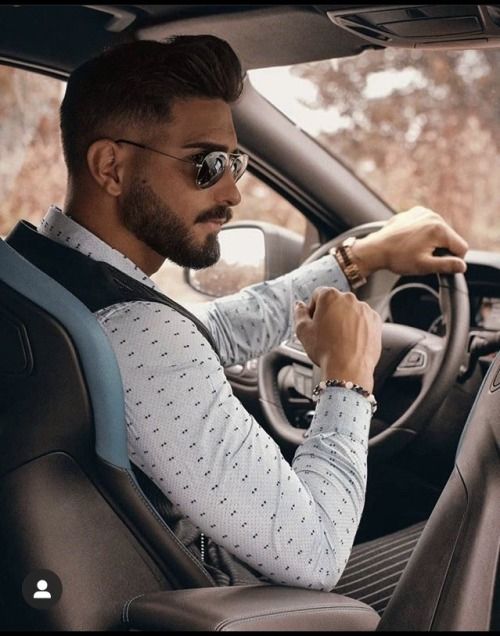 a man sitting in the driver's seat of a car with his hand on the steering wheel