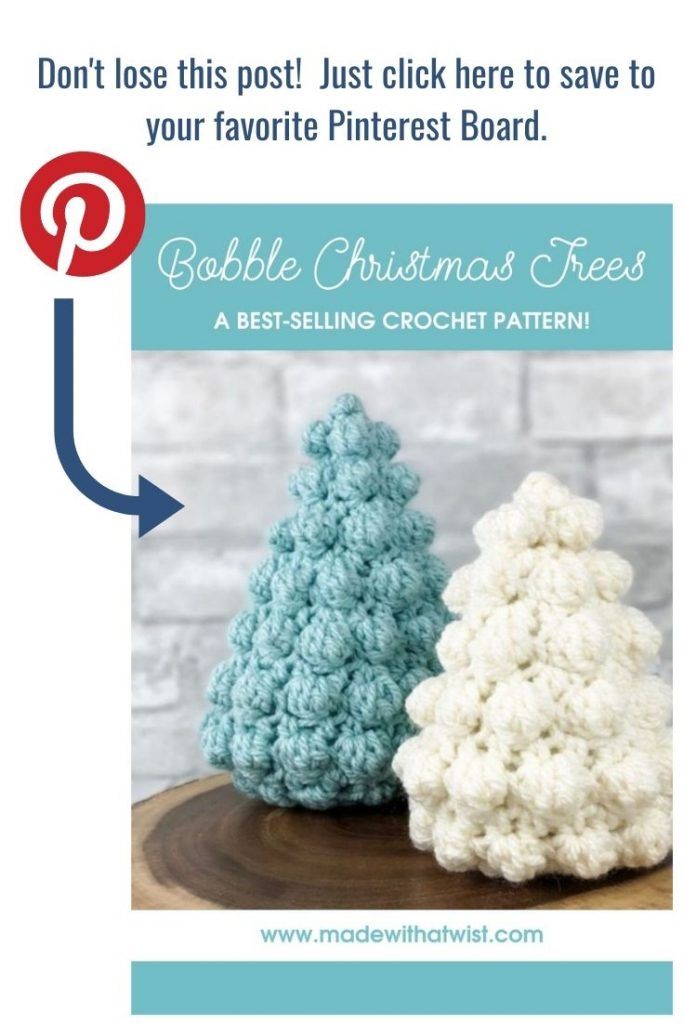 two crocheted christmas trees sitting on top of a wooden table next to each other