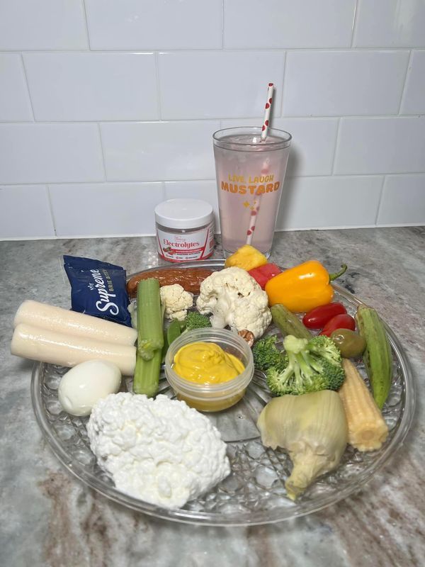 a plate full of vegetables and dips next to a cup with a straw in it