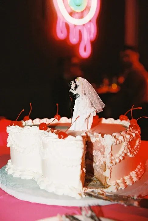 a wedding cake with white frosting and cherries on top