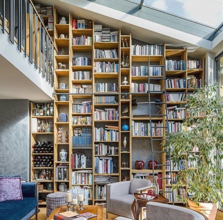 a living room filled with lots of furniture and bookshelves next to a window