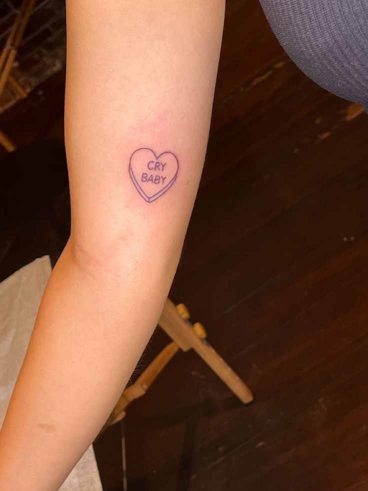 a woman's arm with a tattoo that says baby on it and a heart in the middle