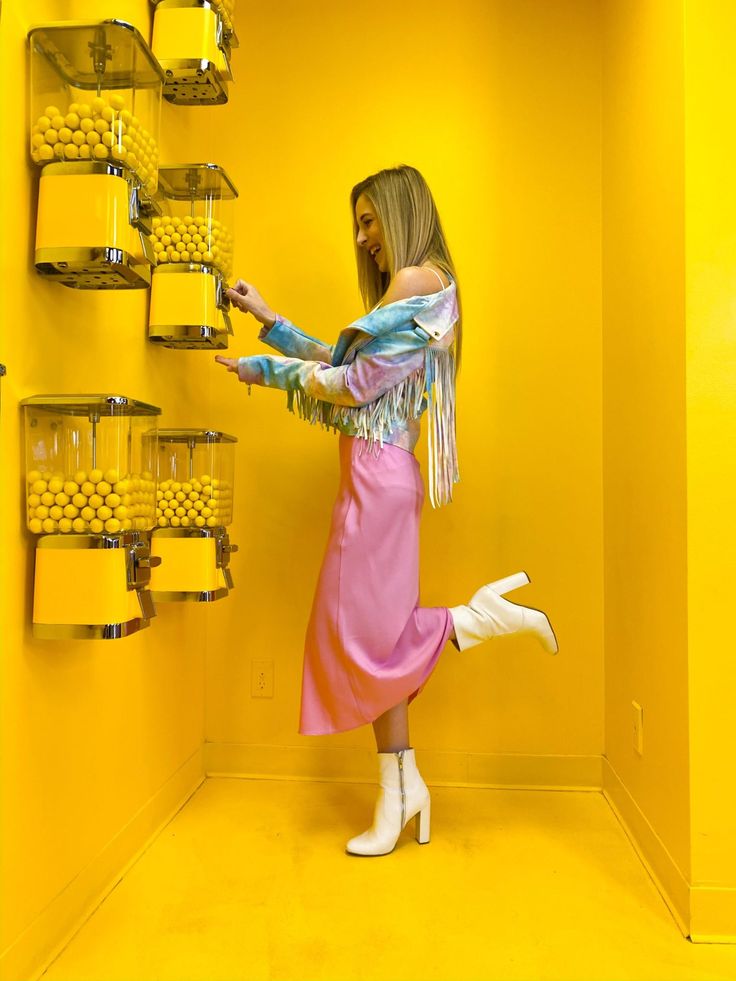 a woman standing in front of a yellow wall with lots of shelves and containers on it