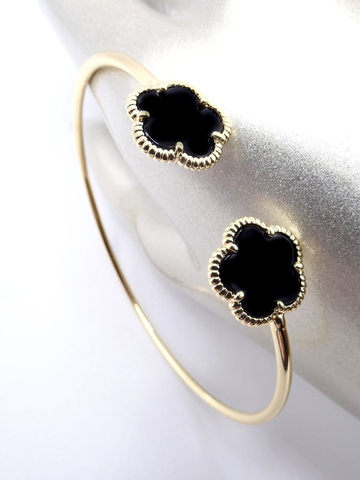 "Luxurious & Classic! This exquisite clover flowers thin cuff bracelet features 18kt gold plated black onyx 5 petal clover flower end tips on thin wire cuff. Measuring 7 1/2\" long, the gorgeous dainty clovers cuff bracelet looks elegant in a timeless sophisticated classic style. ☆ Specifications: * 18kt Gold Plated / Polished Black Onyx Clover Flowers * MEASURES:  7 1/2\" Long * CLOVER FLOWERS:  10mm Diameter ☆ FREE SHIPPING WITHIN THE USA VIA USPS GROUND ADVANTAGE MAIL. INTERNATIONAL SHIPPING IS ONLY $16.95 USD VIA USPS FIRST CLASS EXPEDITED INTERNATIONAL MAIL SERVICE. ☆ THANKS FOR LOOKING!" Black Cuff Bracelet, Minimalist Bangle, Lucky Charm Bracelet, Crystal Cuff Bracelet, Wire Cuff, Clover Flower, Bracelet Dainty, Bridesmaid Bracelet, Black Bracelets