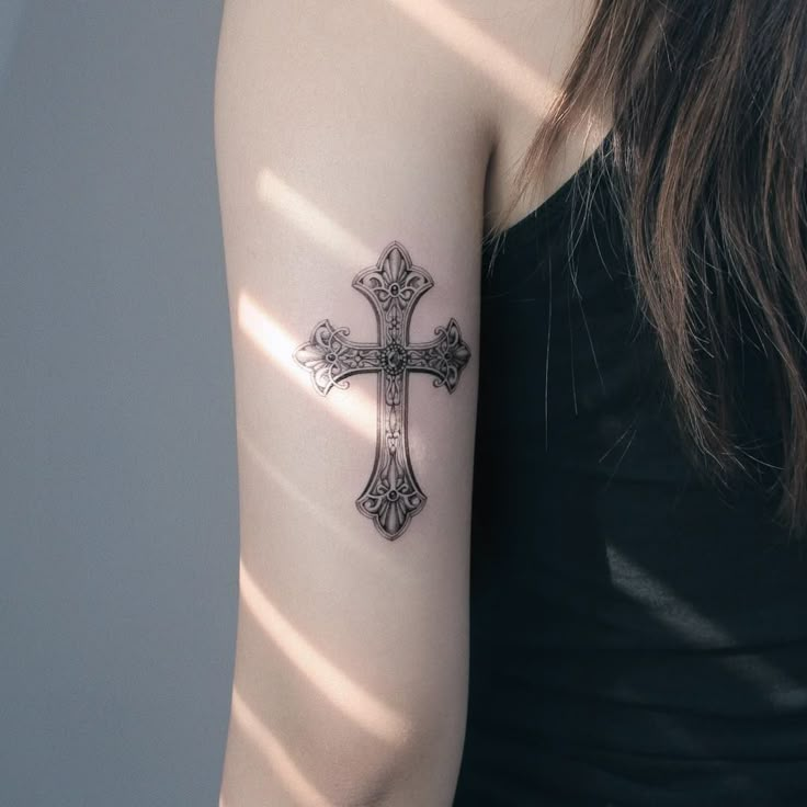 a woman's arm with a cross tattoo on the left side of her arm