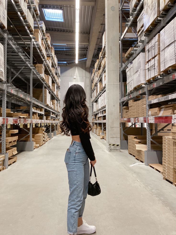 a woman standing in the middle of a large warehouse